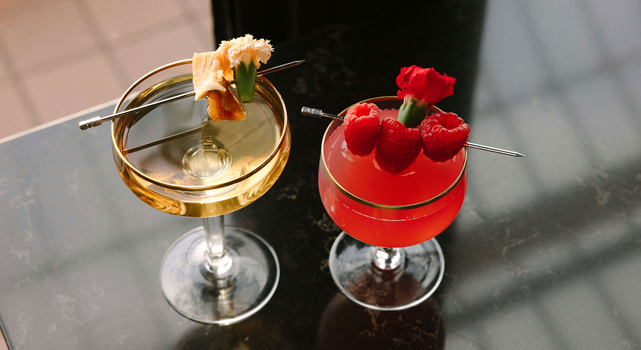 Top down view of yellow and red floral and fruit cocktails side by side - Saskia Potter